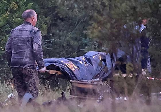 Dos miembros de los equipos de emergencias transportan una bolsa para cadáveres cerca de los restos del avión privado vinculado al jefe de los mercenarios de Wagner, Evgeny Prigozhin