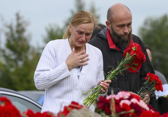 Una pareja llora ante el memorial improvisado en la sede de la empresa en San Petersburgo.