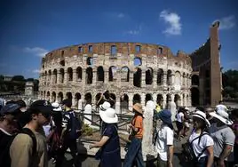 Decenas de turistas pasan ante el Coliseo de Roma