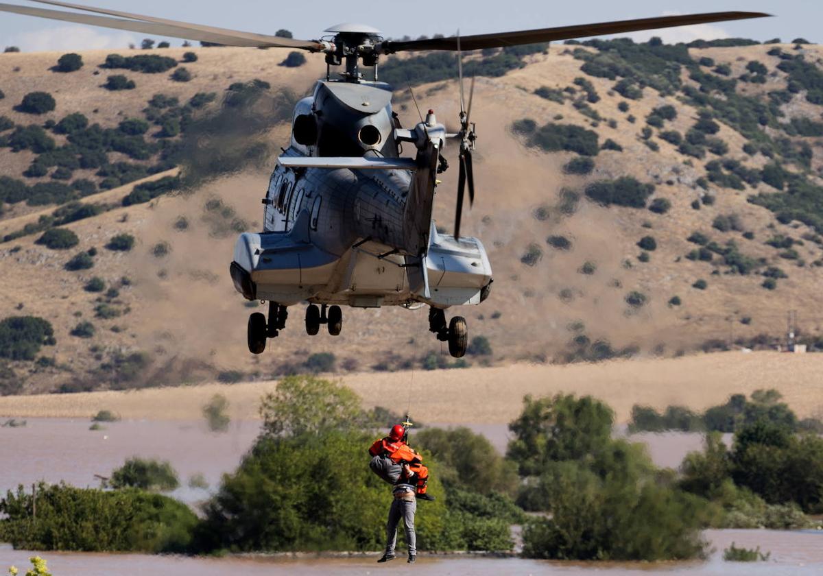 Un helicóptero y su tripulación trabajan para rescatar a una persona varadas en una zona inundada