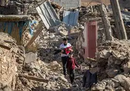 Dos hombres y dos niños pasan junto a casas destruidas en el pueblo de montaña de Tafeghaghte, al suroeste de la ciudad de Marrakech.