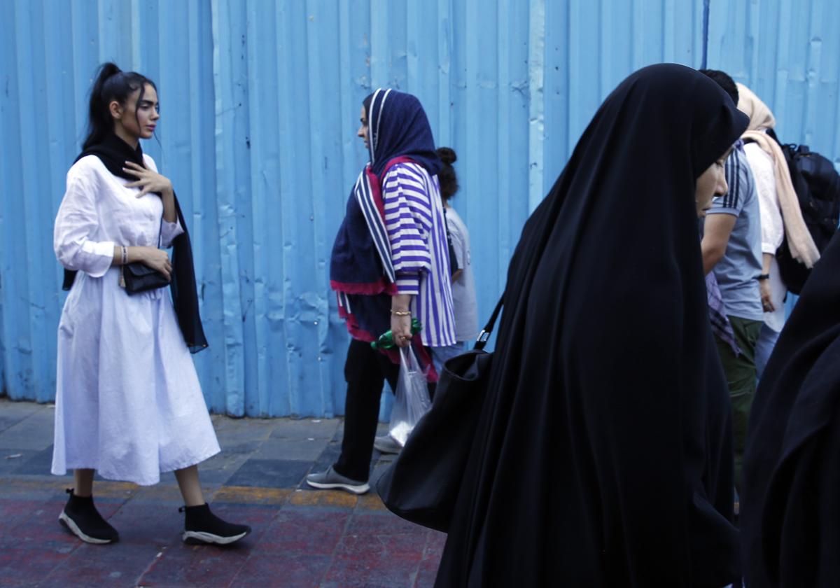 Las mujeres iraníes, algunas sin el velo obligatorio, caminan por una calle en Teherán