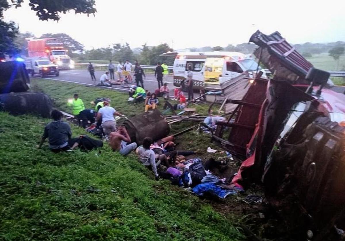 Varios migrantes esperan a ser atendidos al lado del camión volcado.