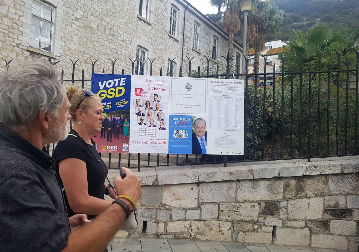 Imagen principal - Una pareja de turistas camina ante uno de los carteles de la campaña electoral. El anticuario Samuel Benzaquen muestra las llaves de sus antepasados judíos de Lucena y una camiseta de una tienda de souvenirs en la calle principal de Gibraltar, Main Street.