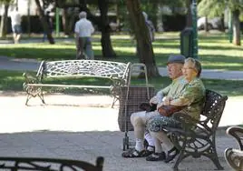 Una pareja de jubilados descansa en el banco de un parque.