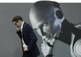 Un hombre conversa por teléfono con la imagen de un robot 'pensativo' al fondo