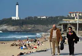Una pareja de jubilados paseando por una playa.