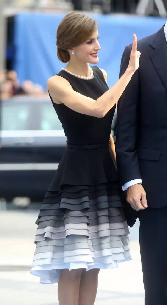 2015. La Reina, en los ya Premios Princesa de Asturias, lució un vestido de Varela en seda cady con cuerpo ajustado de color negro y falda asimétrica cortada en volantes en tonos grises y negros. Fue una prenda polémica, pues muchos consideraron que era muy similar a un diseño de Dior.