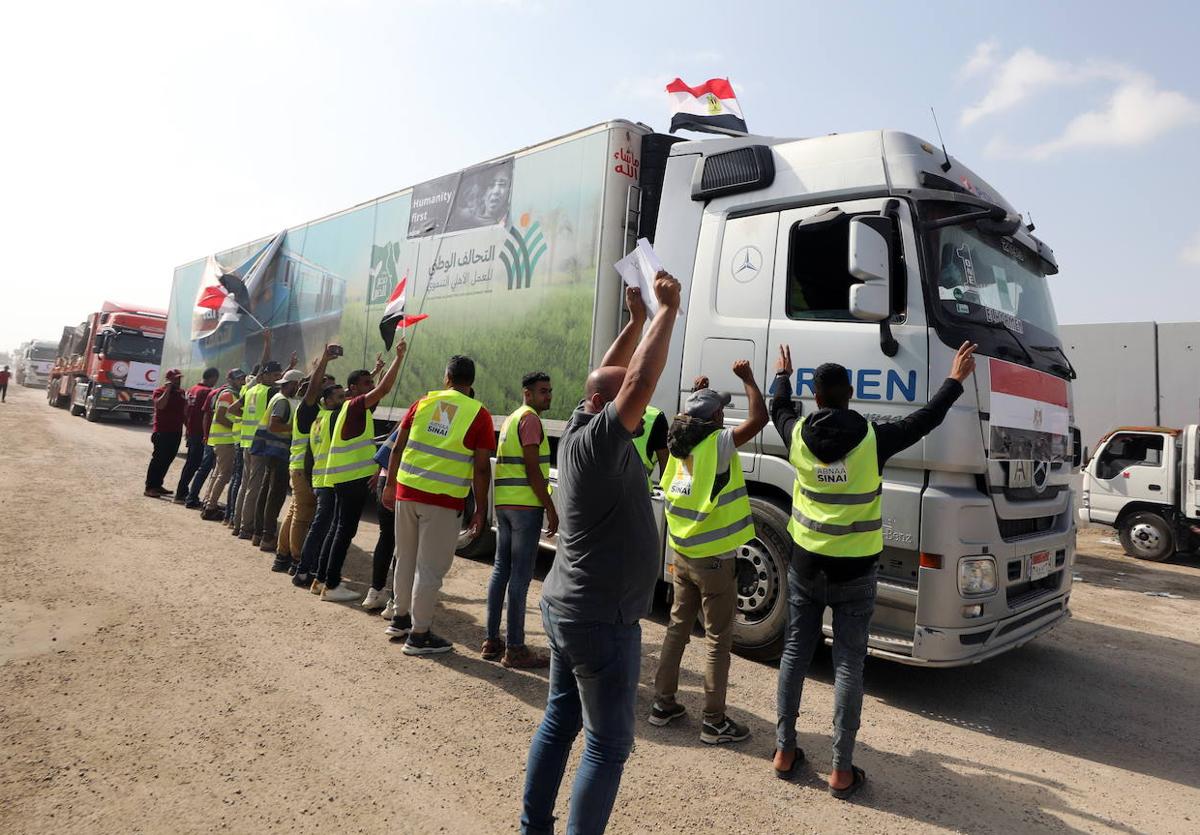 Ciudadanos egipcios saludan al conductor de uno de los camiones que han entrado este domingo en Gaza.