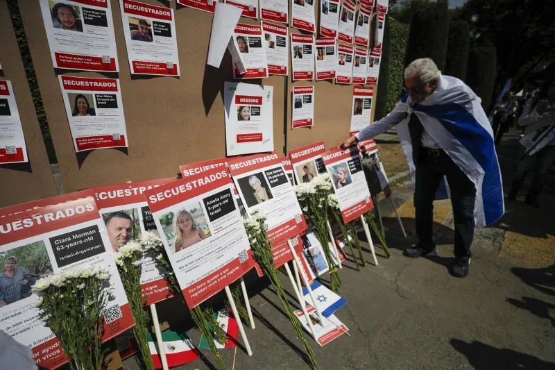 Un hombre observa un panel con las imágenes de los rehenes durante una manifestación a favor de la paz en Gaza.