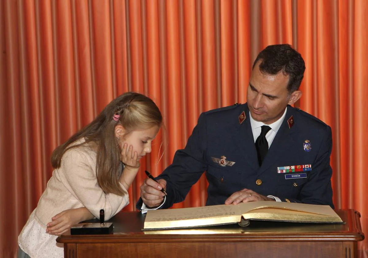 La princesa Leonor observa cómo su padre firma en el libro de honor de la Academia del Aire de San Javier