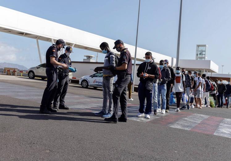 Miembros de la Policía nacional piden los papeles a algunos de los 200 inmigrantes de origen magrebí, que llegaron a las islas en los últimos días en pateras y cayucos, este jueves en el puerto de Santa Cruz de Tenerife y que se trasladan gracias a la Cruz Roja a un hotel del sur de Tenerife