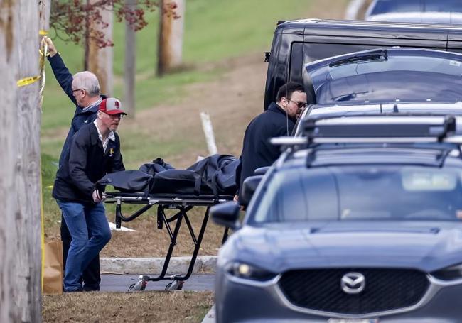 Los equipos funerarios retiran el cadáver de una de las víctimas.