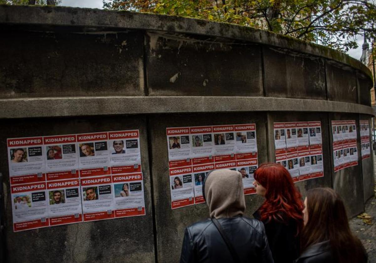 Un grupo de jóvenes observa en un muro fotografías de las personas retenidas ppr Hamás.