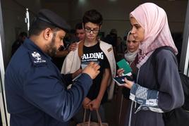 Una familia palestina con doble nacionalidad espera a que un agente revise su documentación en el paso de Rafah.