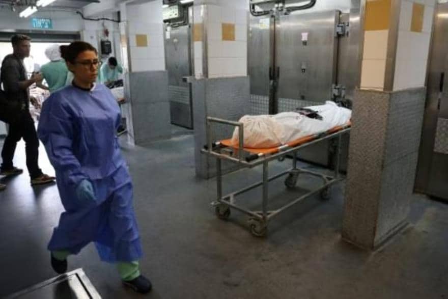A doctor walks past the body of a massacre victim in the Tel Aviv morgue.