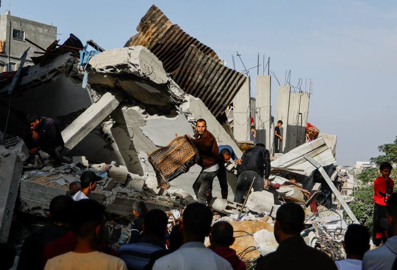 Ciudadanos gazatíes rescatan enseres de una casa bombardeada.