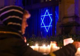 Una mujer enciende una vela en una sinagoga de la localidad alemana de Colonia para conmemorar el 85 aniversario de la llamada Noche de los Cristales Rotos.