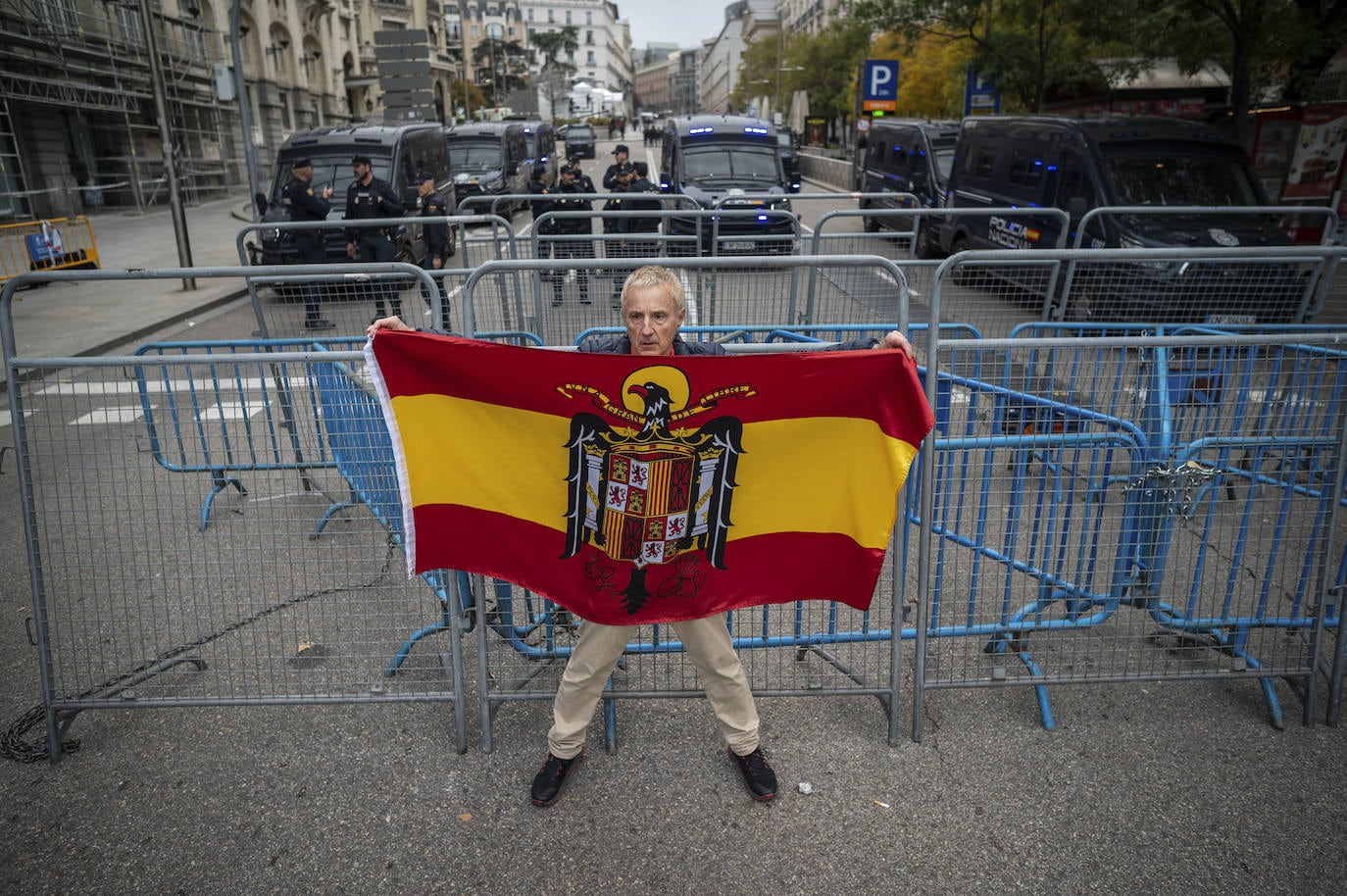 Un manifestante muestra una bandera preconstitucional ante las vallas montadas por la policía en los alrededores del Congreso de los Diputados.
