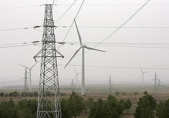 Vista de lineas electricas enfrente de un aerogenerador.