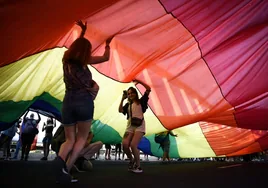 Un grupo de ciudadanos sostiene una gran bandera LGTBI el día del Orgullo, en Valencia.