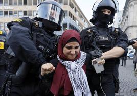 Dos agentes de policía retiran a una participante de una manifestación propalestina en Frankfurt