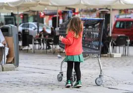 Una niña camina junto a la terraza de un bar en el centro de Madrid.