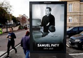 Un grupo de parisinos camina frente a una marquesina en la que se muestra un retrato de Samuel Paty, el profesor decapitado en octubre de 2020.