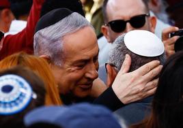 El primer ministro israelí, Benjamín Netanyahu, consuela a un miembro de su gabinete en el funeral de su hijo, un soldado israelí fallecido en el norte de Gaza.