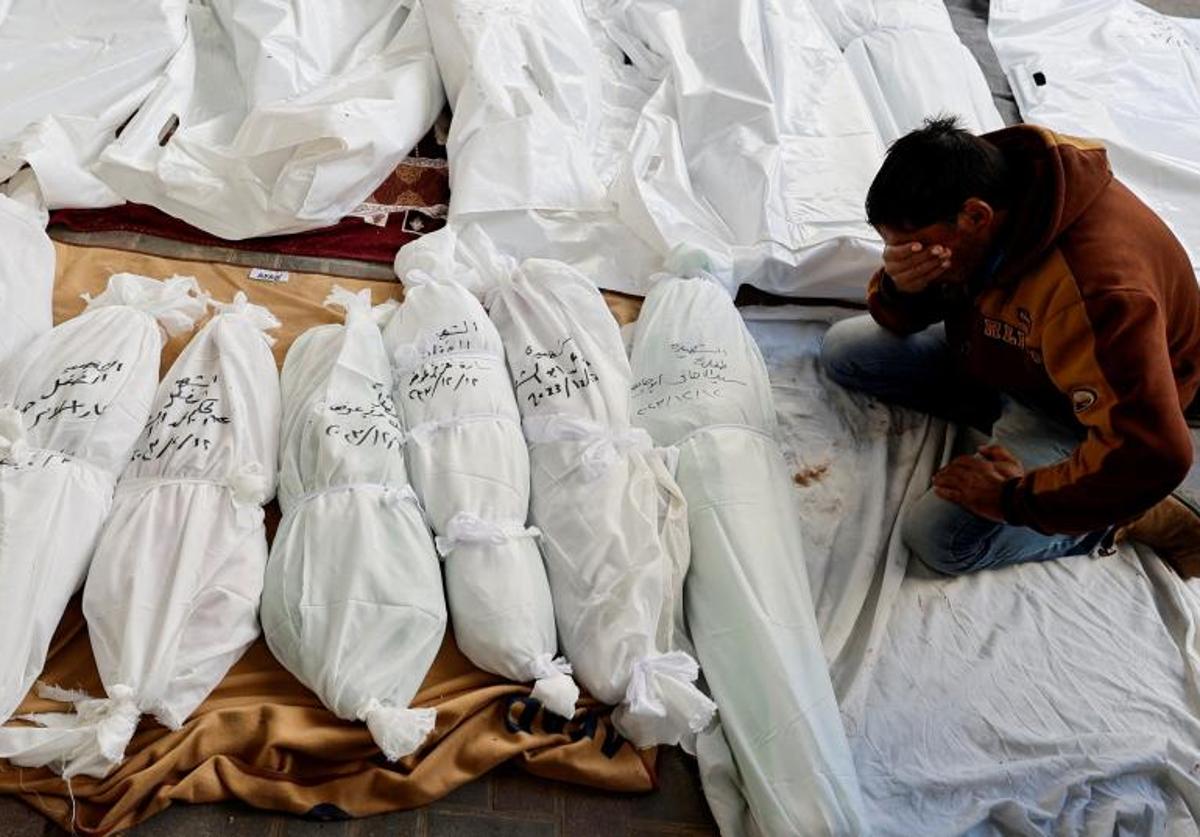 Un hombre llora ante una hilera de cadáveres de palestinos en un hospital del sur de Gaza.