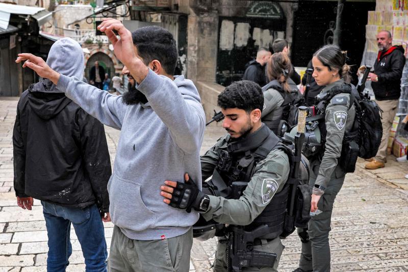 İsrailli bir sınır görevlisi, yoğun güvenlik önlemlerinin alındığı Kudüs'te Filistinli bir adamı arıyor.