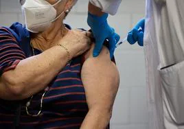 Una enfermera vacuna a una mujer mayor en un centro de salud