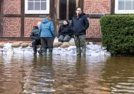 Los residentes se reúnen frente a una casa protegida por sacos de arena en una calle inundada en Verden