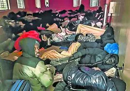 Africanos recién llegados dormitan amontonados en un sótano.