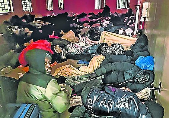 Africanos recién llegados dormitan amontonados en un sótano.