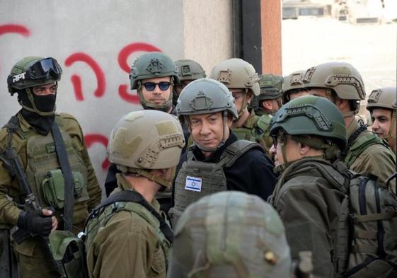 Netanyahu, protegido con casco y chaleco antibalas, habla con varios soldados durante una visita al frente del norte de Gaza.