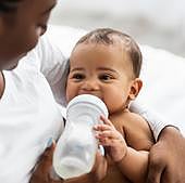 Bebe bebiendo de un biberón de plástico.