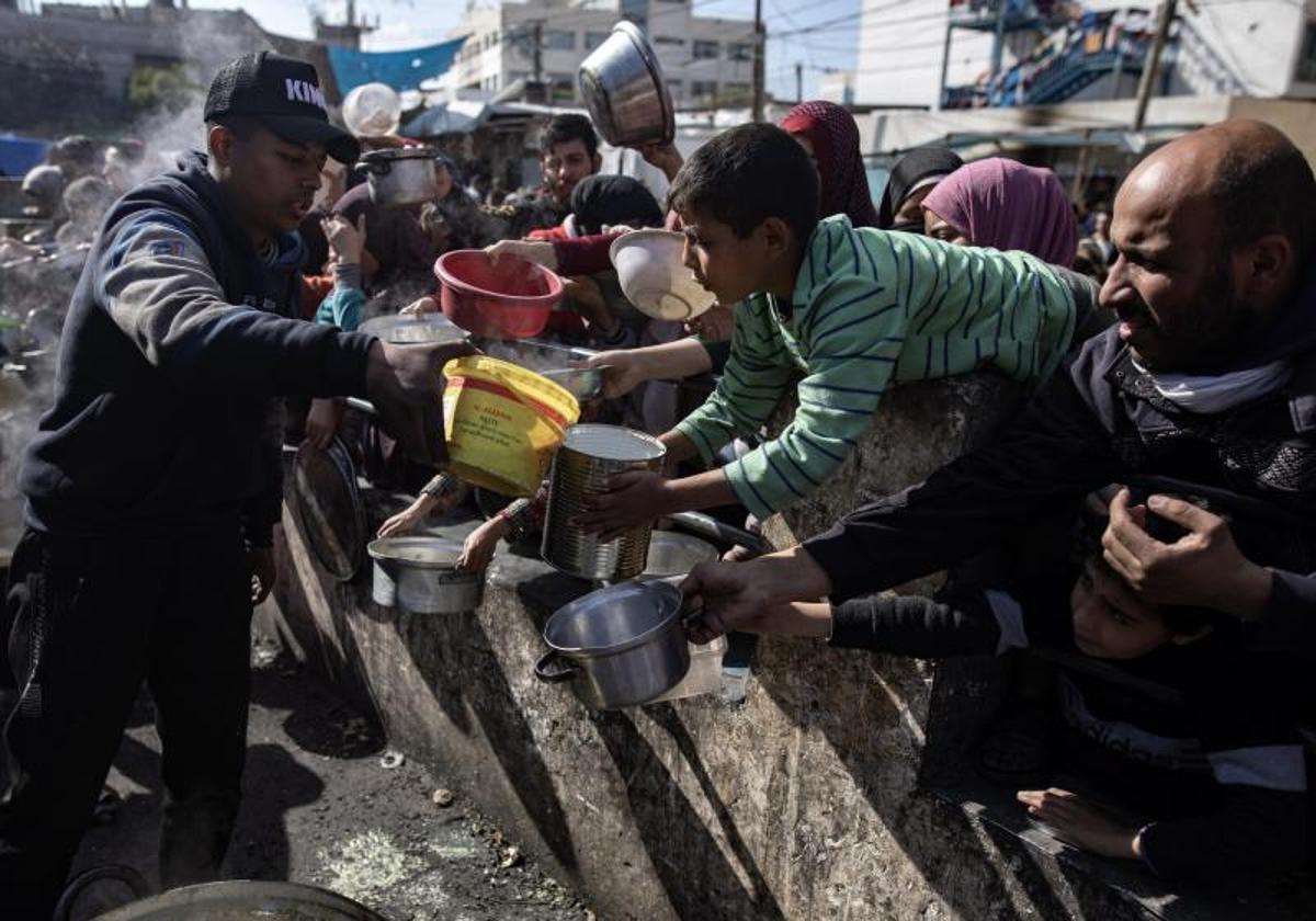 Un grupo de palestinos recibe ayuda alimentaria en el campo de refugiados de Rafah.