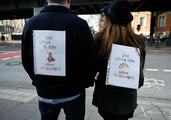 Dos jóvenes llevan carteles con los colores del arcoíris durante una manifestación contra el racismo y la política de extrema derecha.