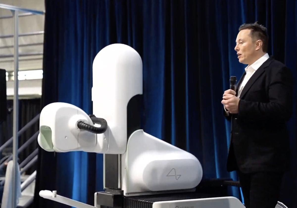 Musk, con el robot que implanta el dispositivo en el cerebro.