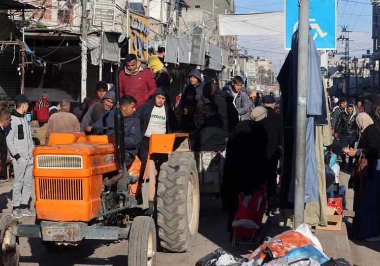 Varias personas utiliza un tractor como medio de transporte en Rafah.