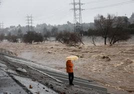 Un hombre con un paraguas observa el río los Ángeles durante las fuertes lluvias que azotan California.
