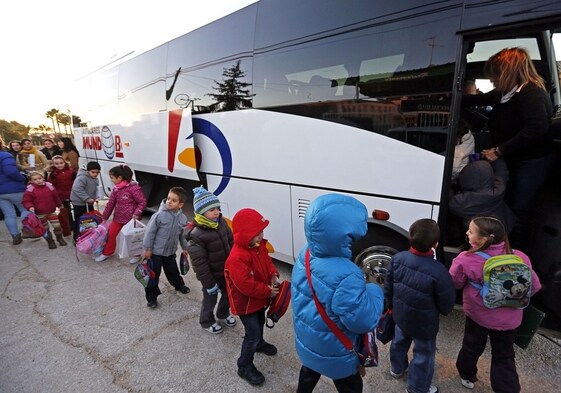 Un grupo de niños hace fila para subir a un autobús escolar.