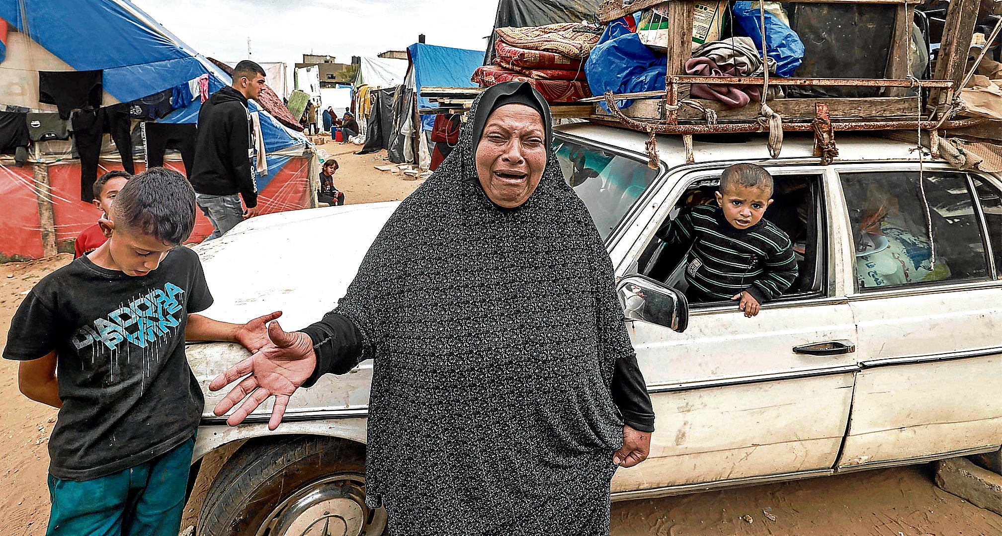 Una mujer llora tras cargar todo lo que aún tiene en un coche para salir huyendo de Rafah.