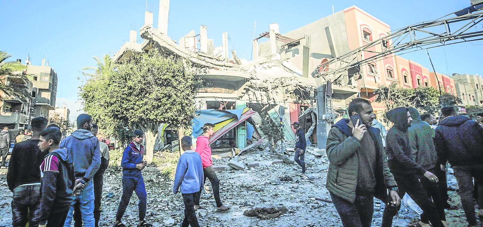 Ciudadanos de la Franja de Gaza junto a un edificio en ruinas.