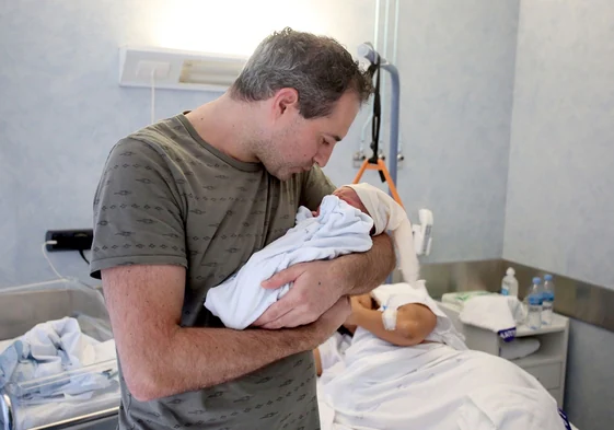 Un padre sostiene a su hijo recién nacido en la habitación del hospital.