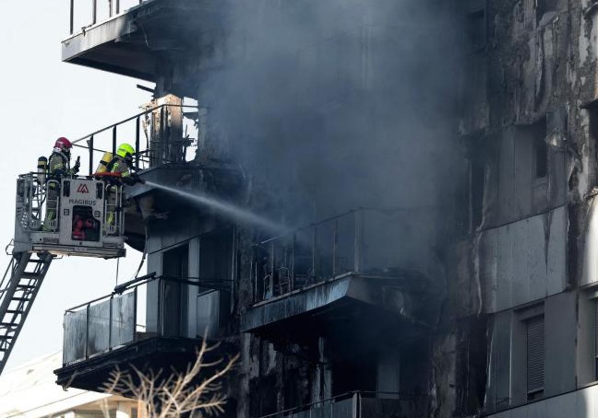 Los bomberos refrescan el edificio una vez controlado el incendio.