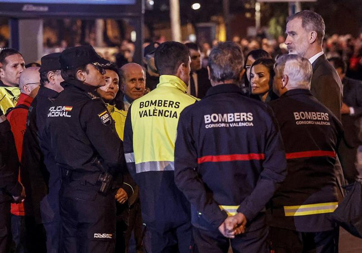 Imagen principal - Los Reyes saludan a los cuerpos de emergencias que trabajan en el edificio incendiado y saludan a los vecinos afectados.