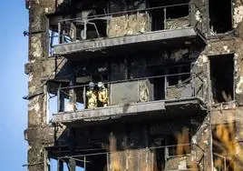 Dos bomberos inspeccionan una de las viviendas arrasadas por el fuego.