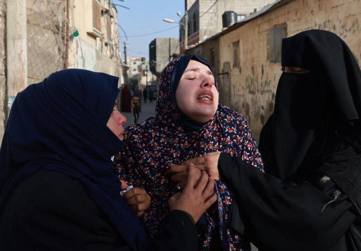 Una madre es consolada por varias vecinas tras perder a sus dos hijos gemelos en un bombardeo en Gaza.